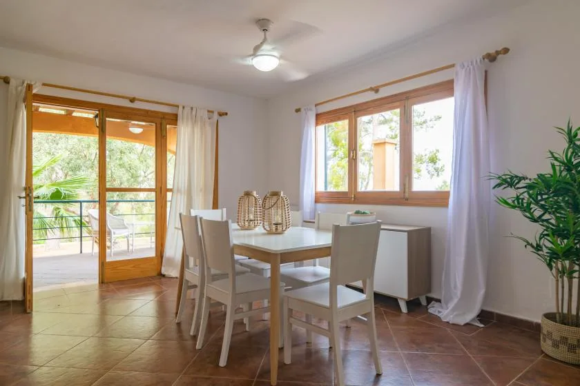 A dining area with a table and chairs beside windows and glass doors.