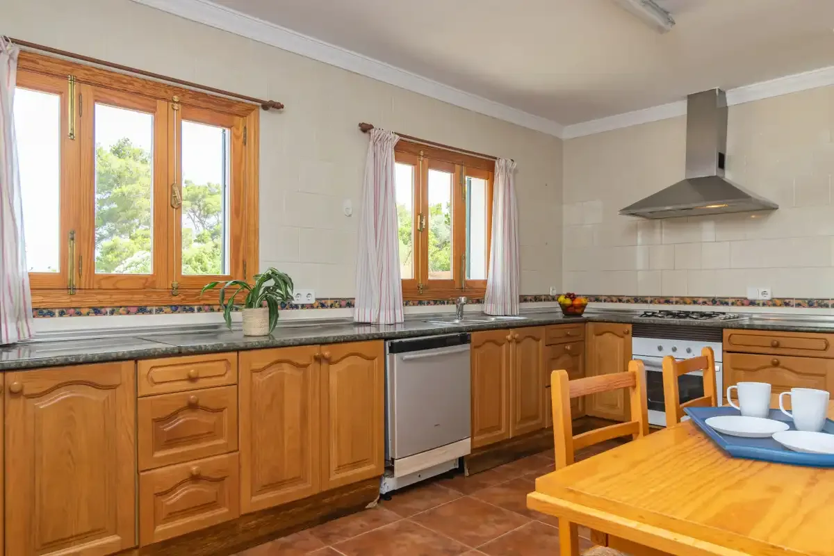 A kitchen with wooden cabinets, a countertop, and a dining table.