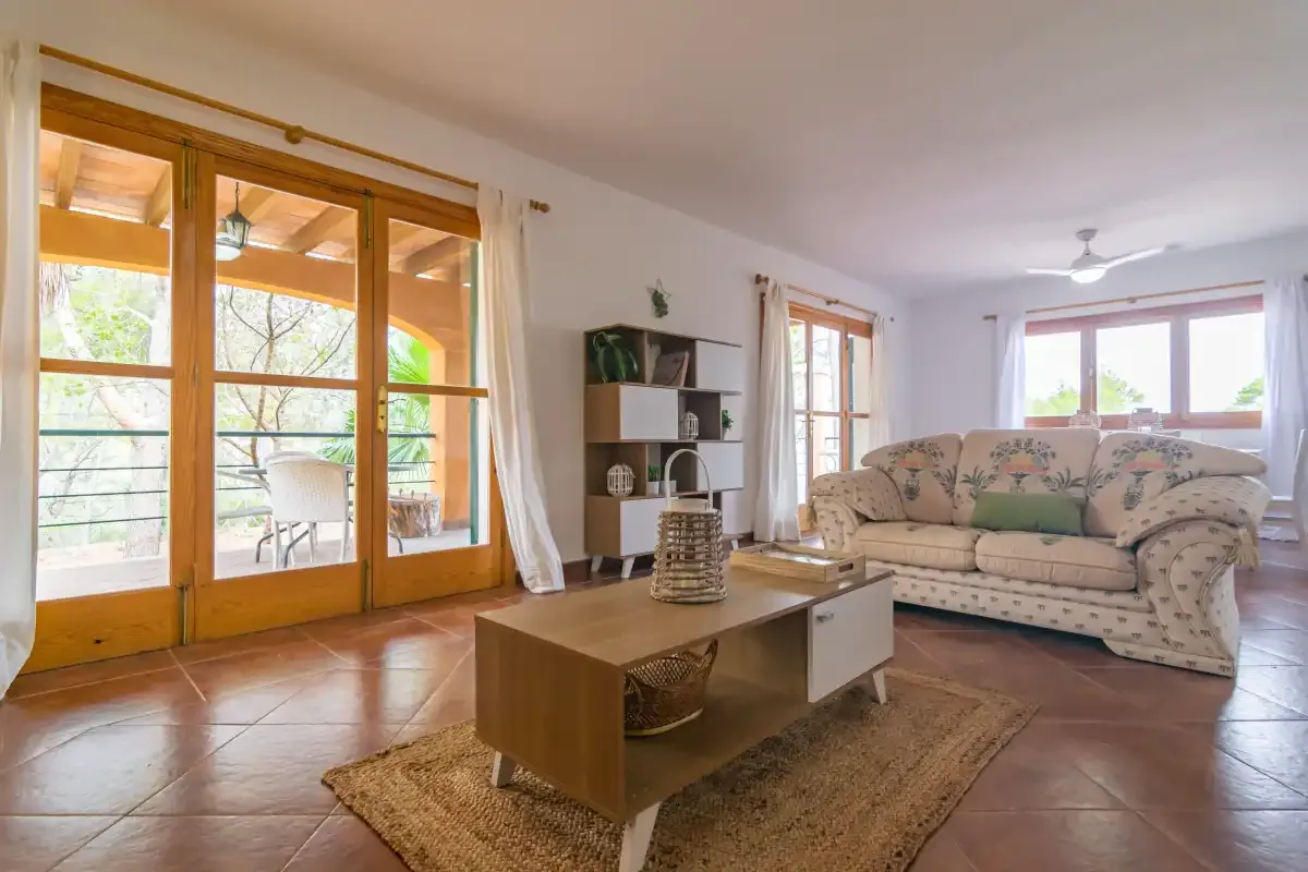 A bright living room with seating, a coffee table, and glass doors opening onto a patio.