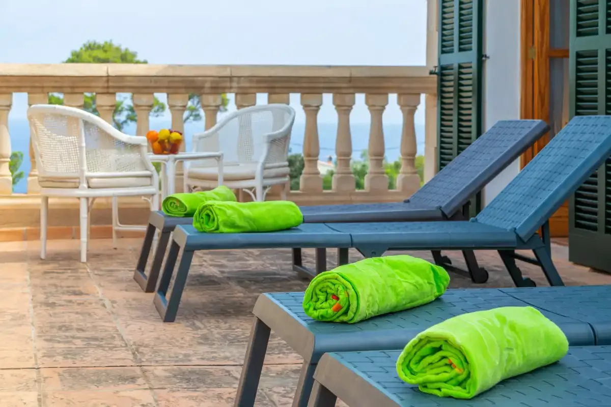 A tiled terrace with blue lounge chairs and bright green towels.