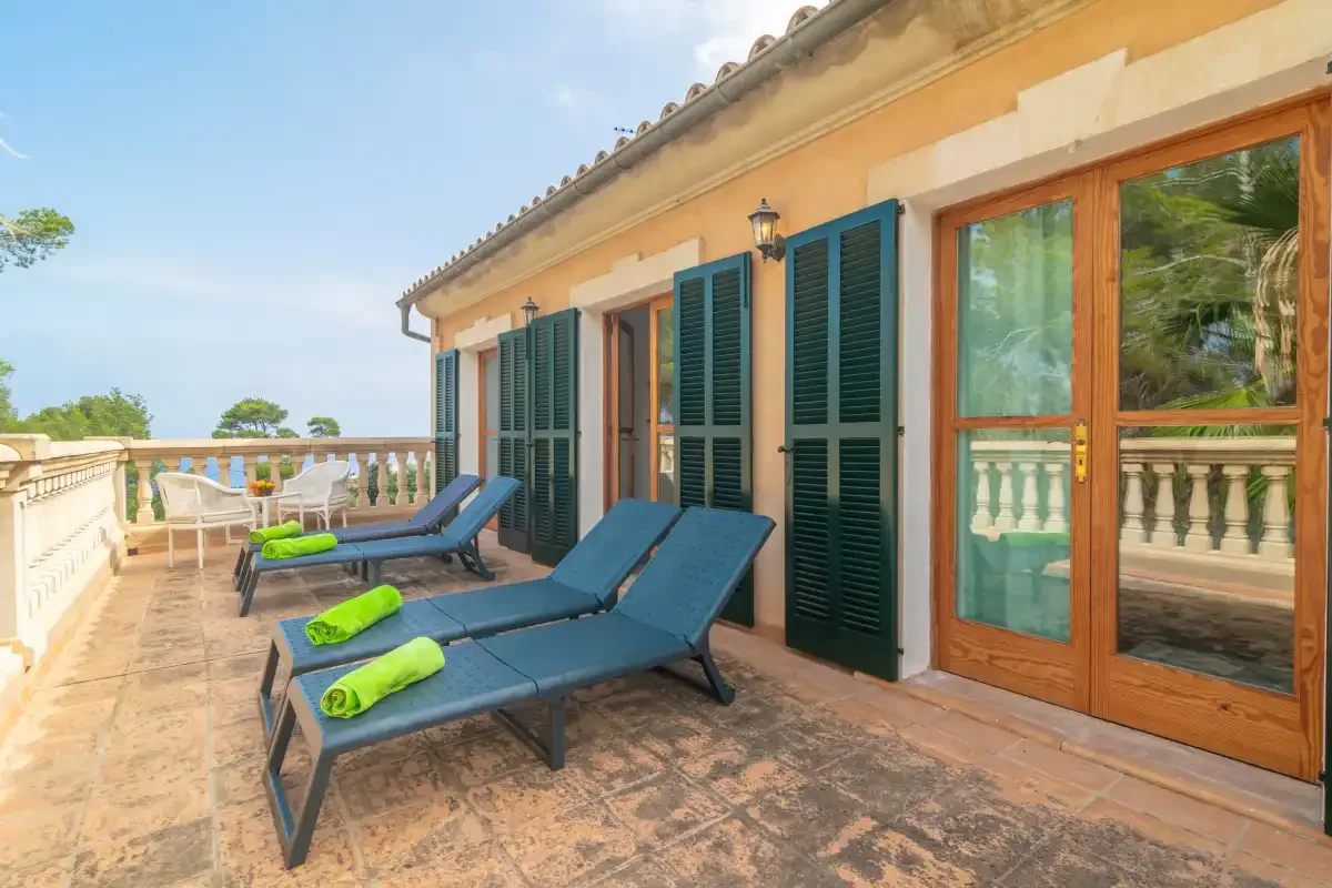 A sunlit terrace with lounge seating beside a house.