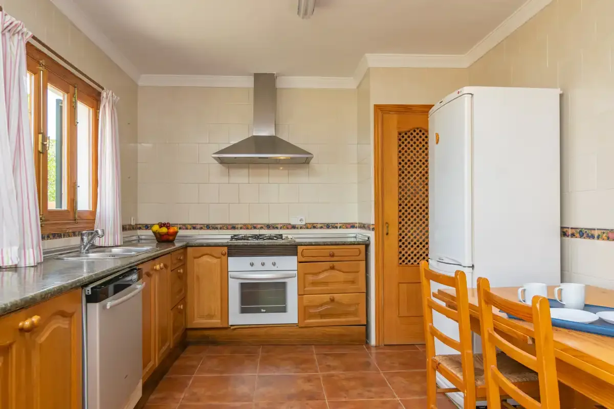 A kitchen with wooden cabinets, a refrigerator, and a dining table.
