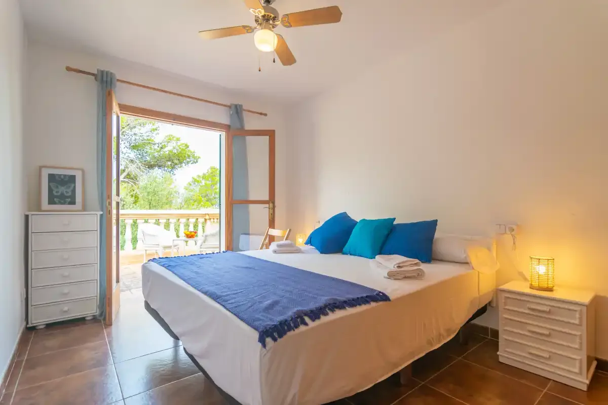 A bedroom with a neatly made bed and blue accent pillows.