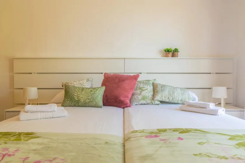 A bedroom with a neatly made bed, colorful pillows, and bedside lamps.