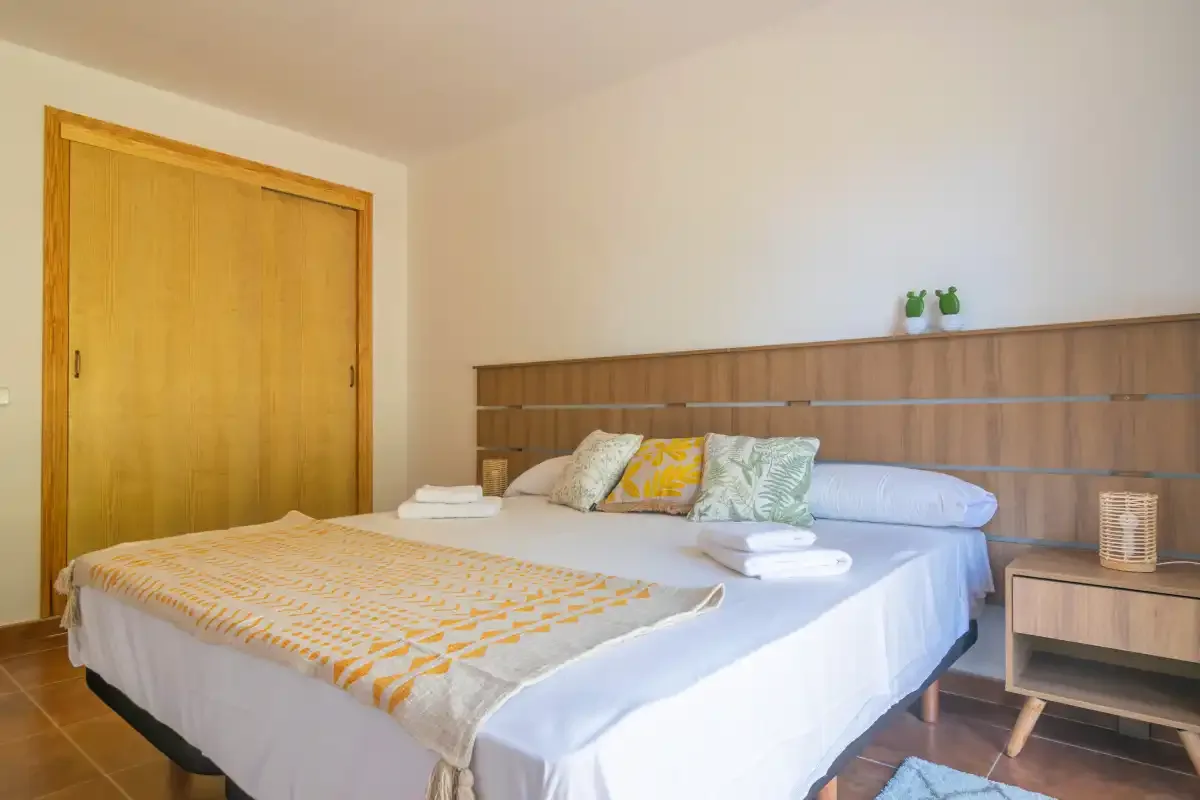 A bedroom with a neatly made bed and wooden headboard.