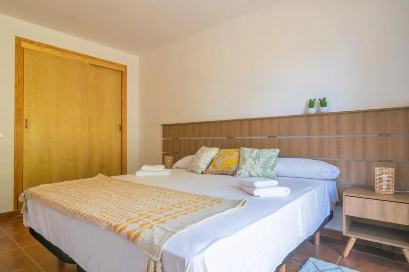 A bedroom with a bed, a wooden headboard, and a sliding wooden door.