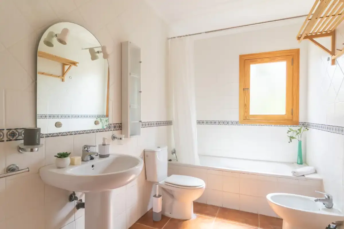 A bright bathroom with a bathtub, sink, and wooden-framed window.