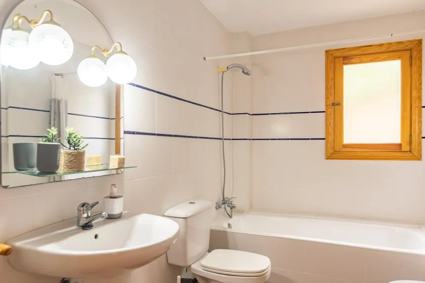 A bathroom with a bathtub, toilet, and sink beneath a mirror.