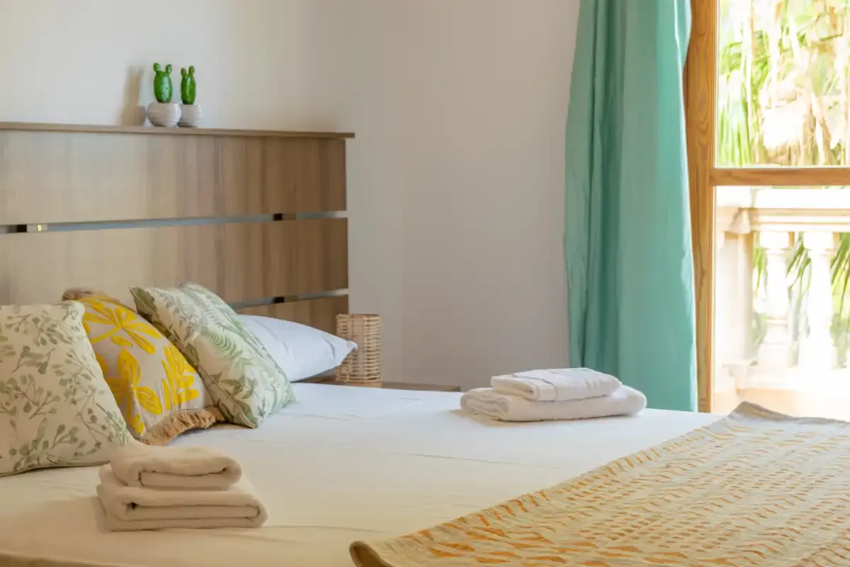 A bedroom with a neatly made bed and folded towels.