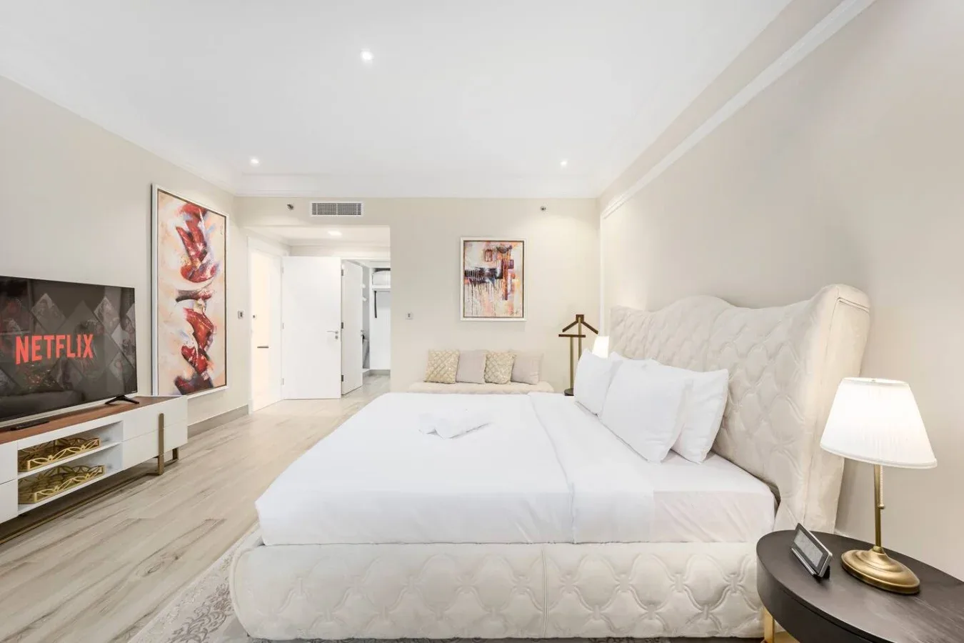 A bright bedroom with a large bed, bedside table, and television.