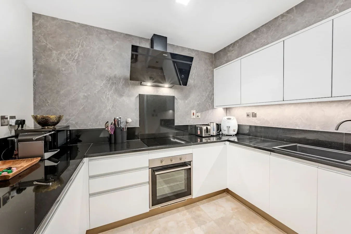A modern kitchen with white cabinets, dark countertops, and built-in appliances.