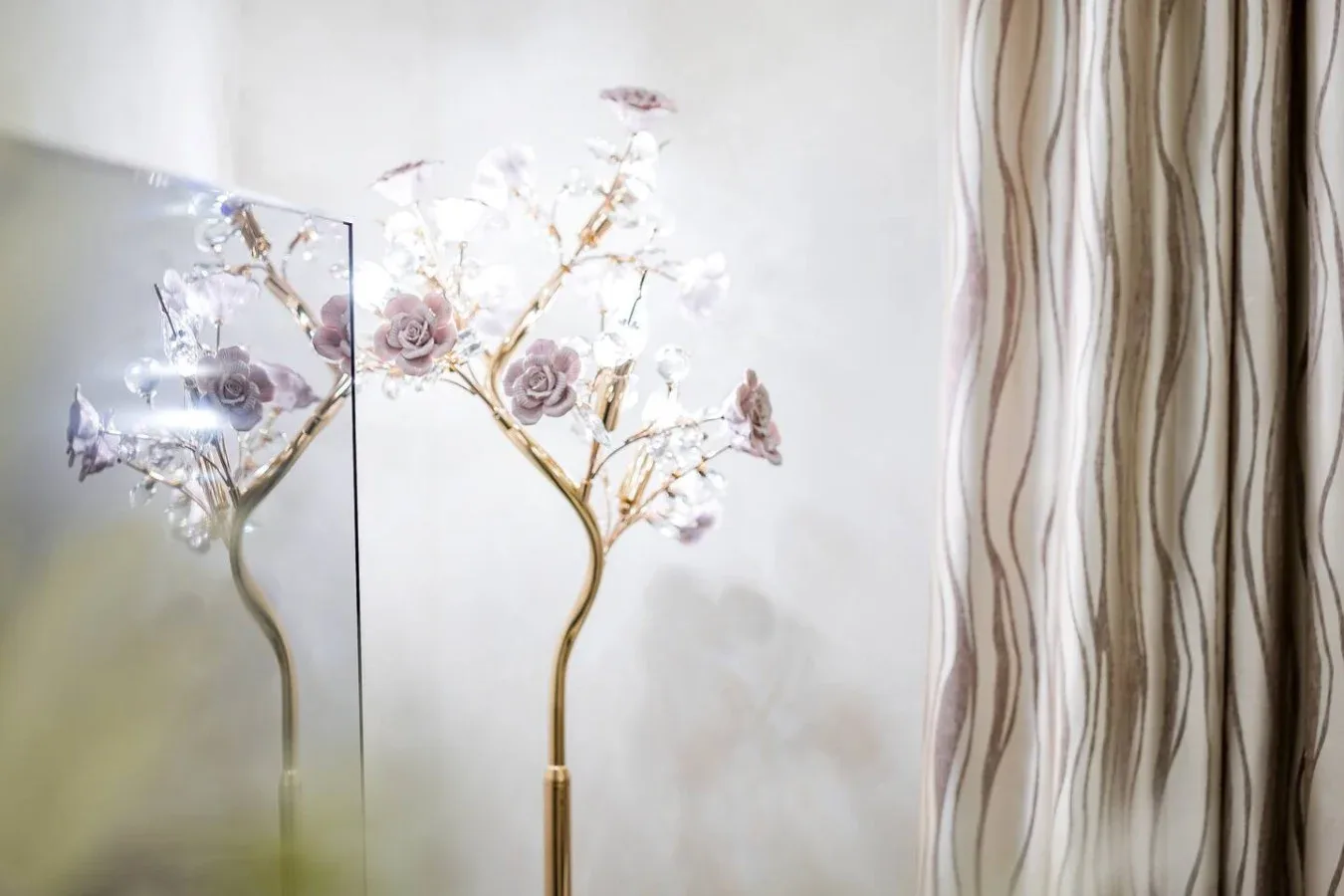 A decorative floral lamp stands beside patterned curtains.