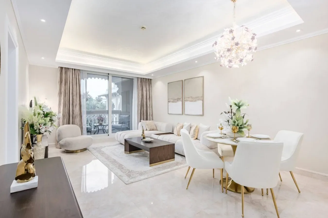 A bright living and dining room with pale seating, a coffee table, and a chandelier.