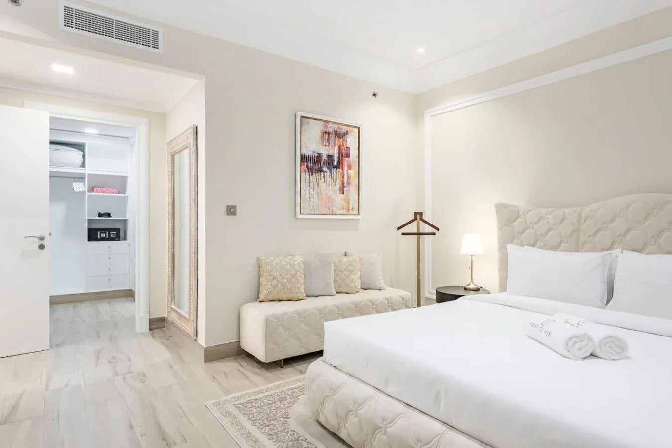 A bright bedroom with a large bed, a small sofa, and framed wall art.