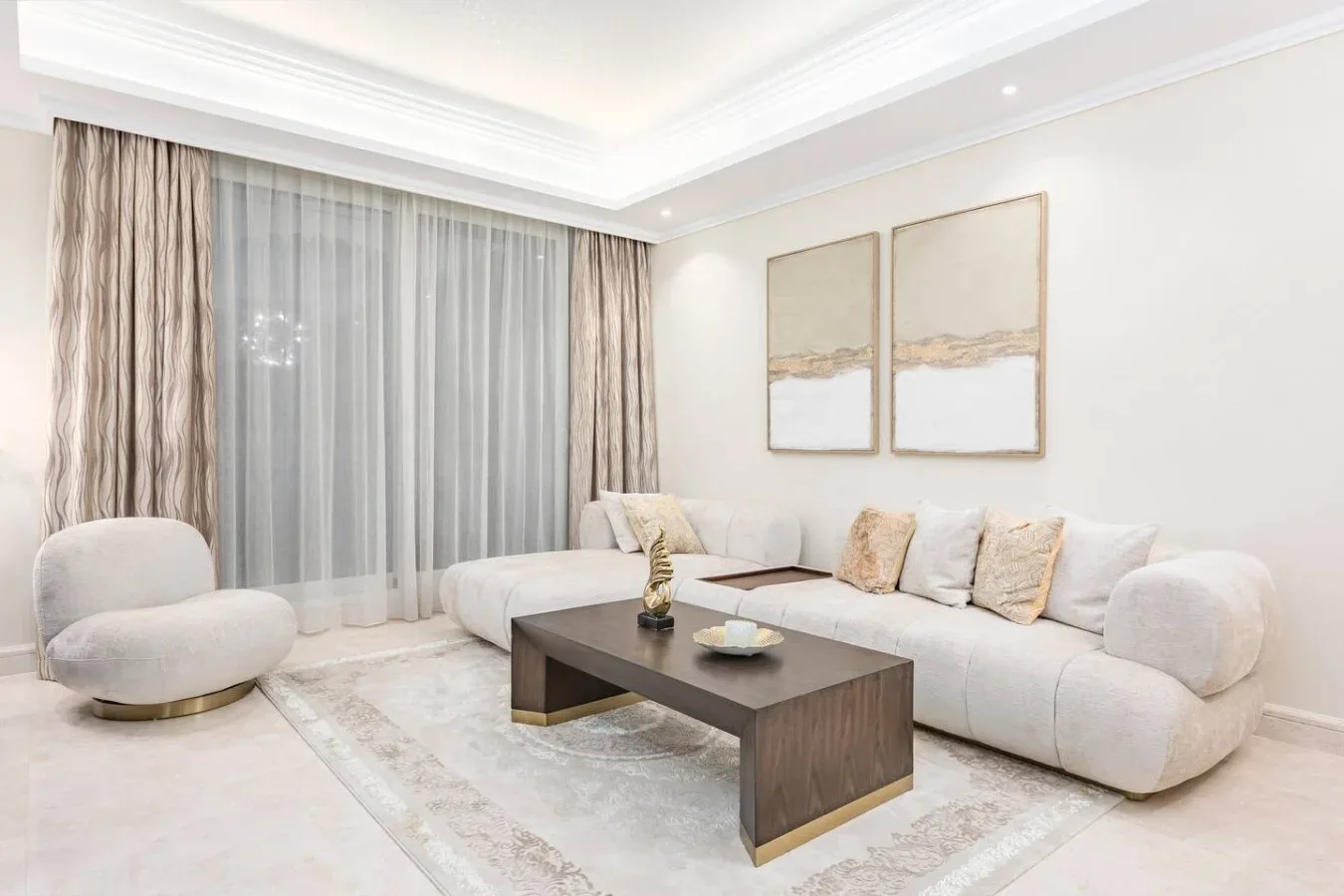 A bright living room with a sectional sofa, coffee table, and floor-to-ceiling curtains.