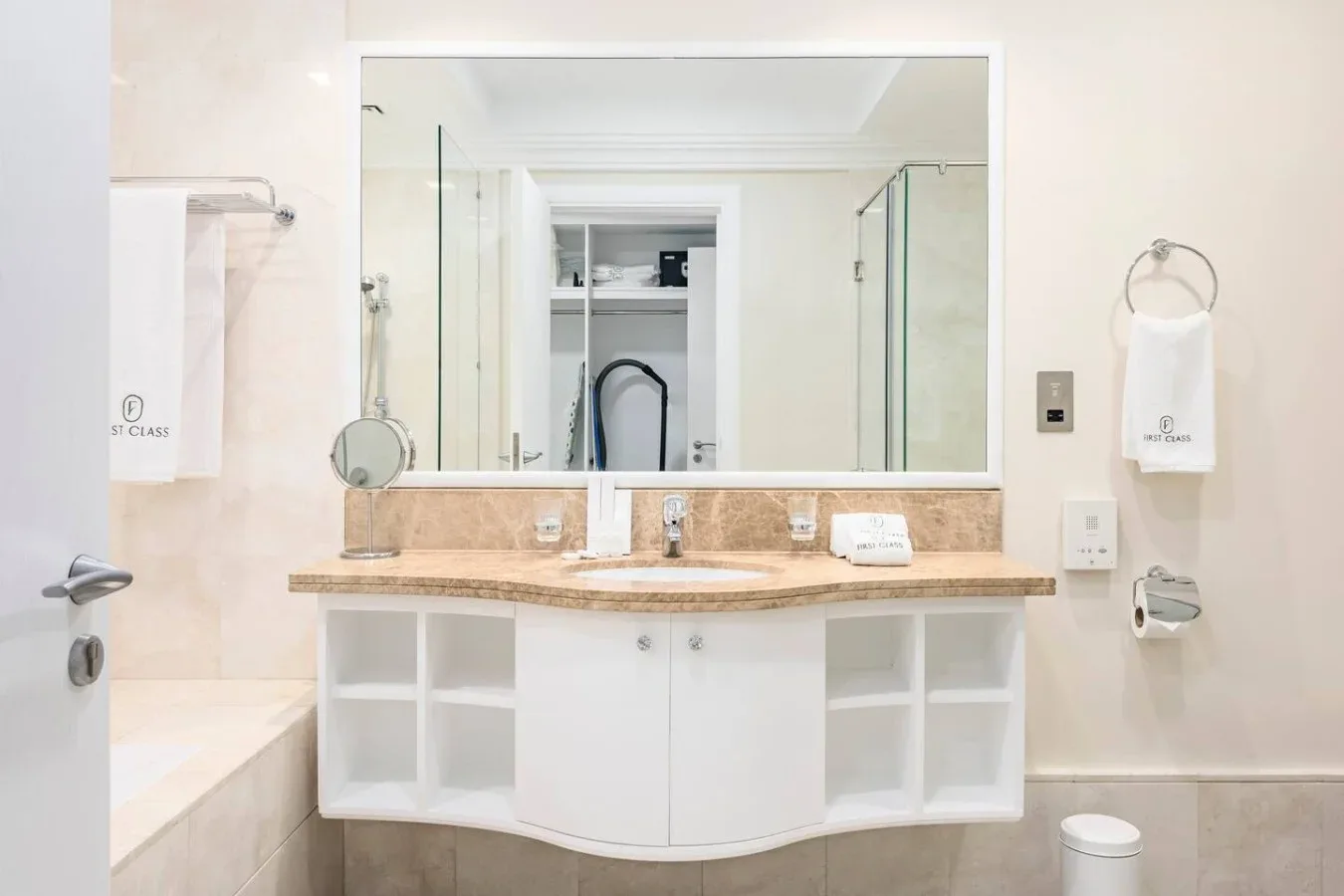 A bright bathroom with a wide mirror above a curved vanity.