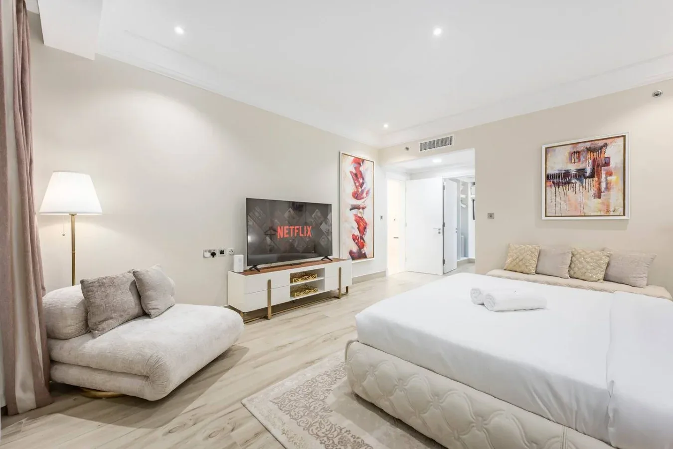 A bright bedroom with a large bed, seating area, and television.