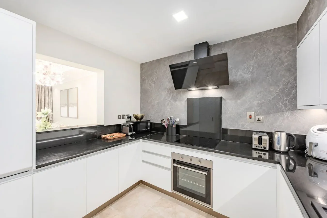 A modern kitchen with white cabinets, dark countertops, and built-in appliances.