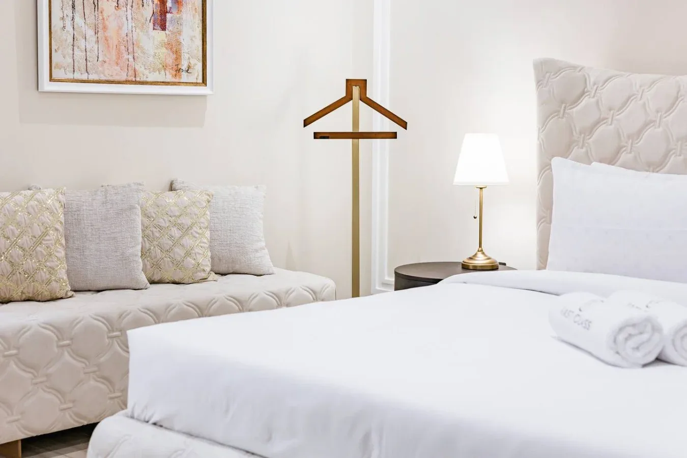 A bright bedroom with a neatly made bed and a cushioned seating area.