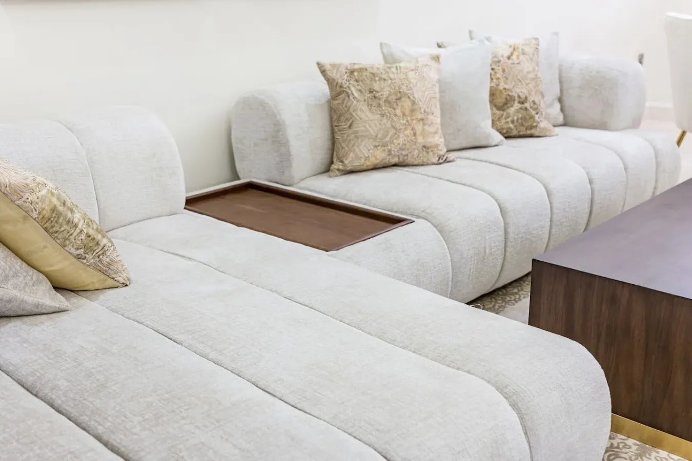 A bright living room with pale sectional seating and decorative cushions.