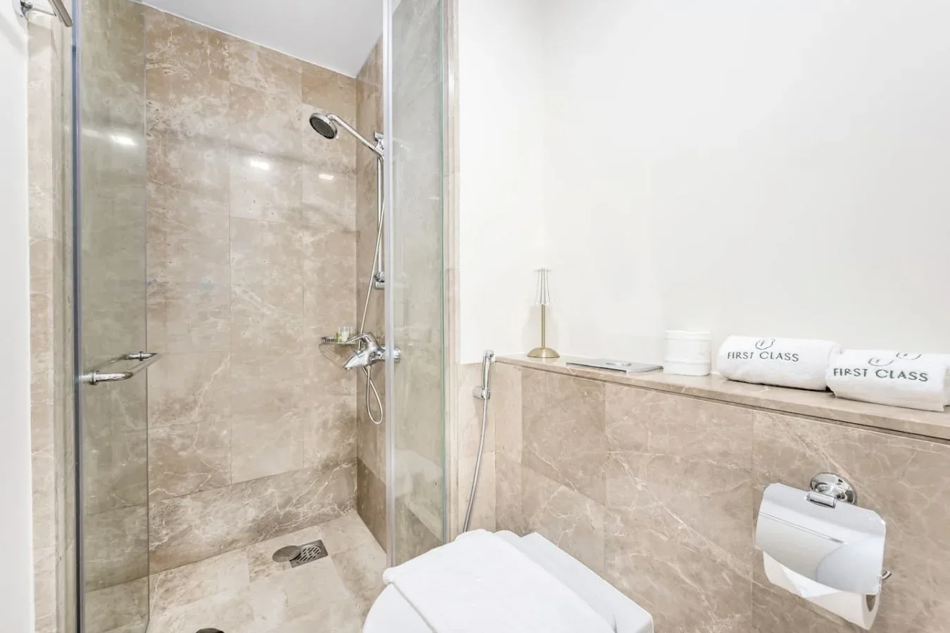 A bathroom with a glass shower and folded white towels.