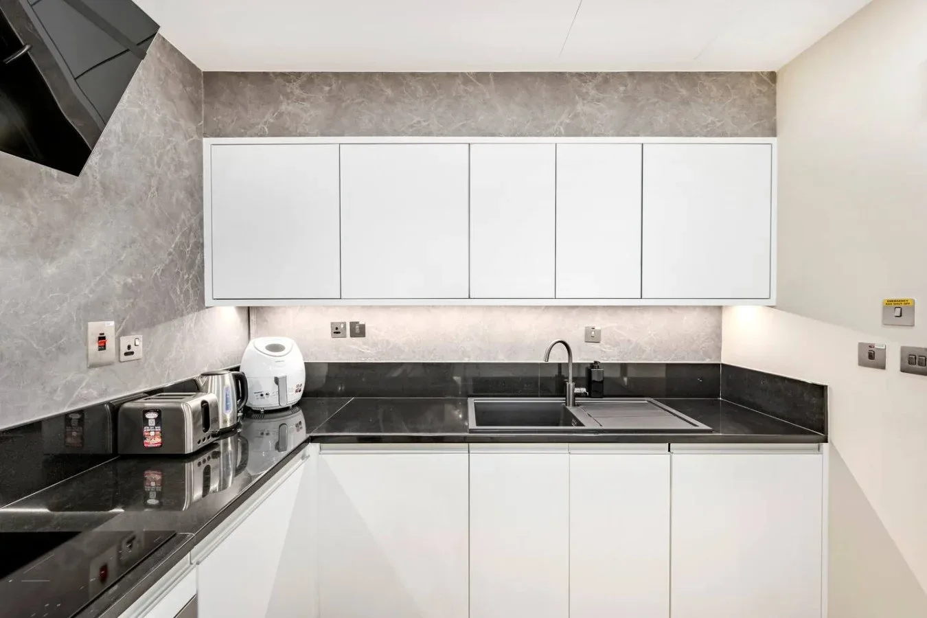 A modern kitchen with white cabinets and a dark countertop.