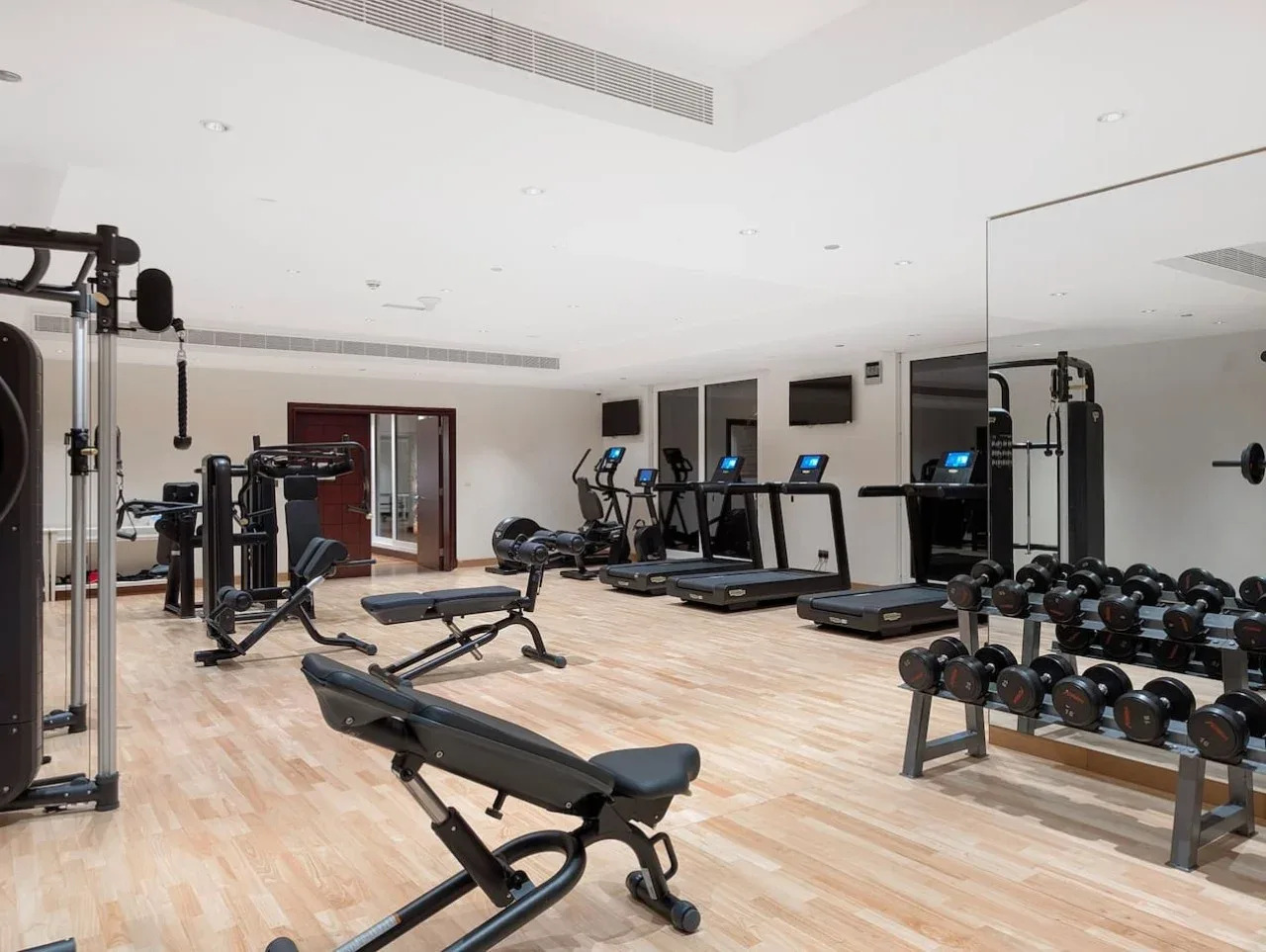 A fitness room with exercise machines, treadmills, and weights.