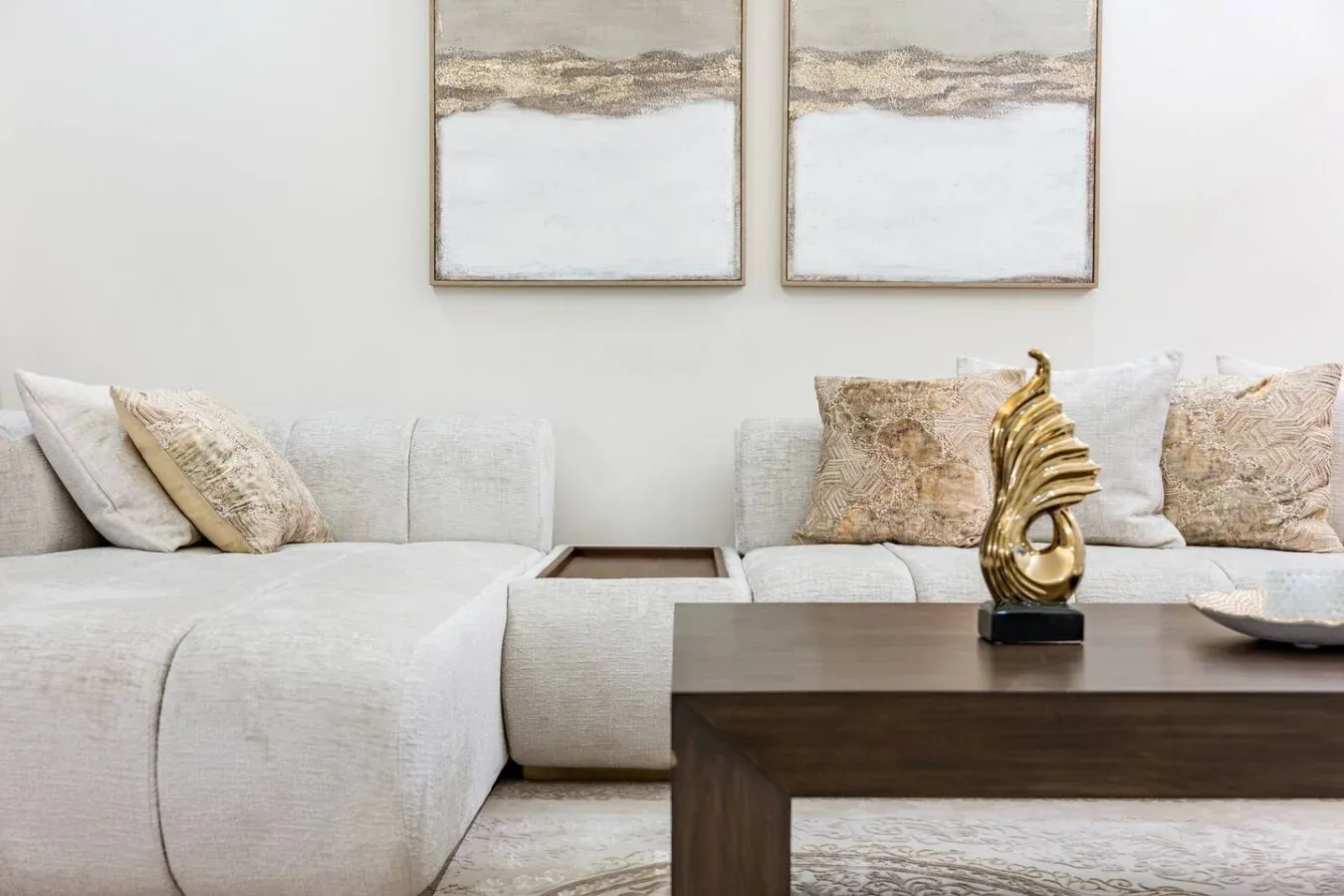 A bright living room with pale seating and abstract artwork on the wall.