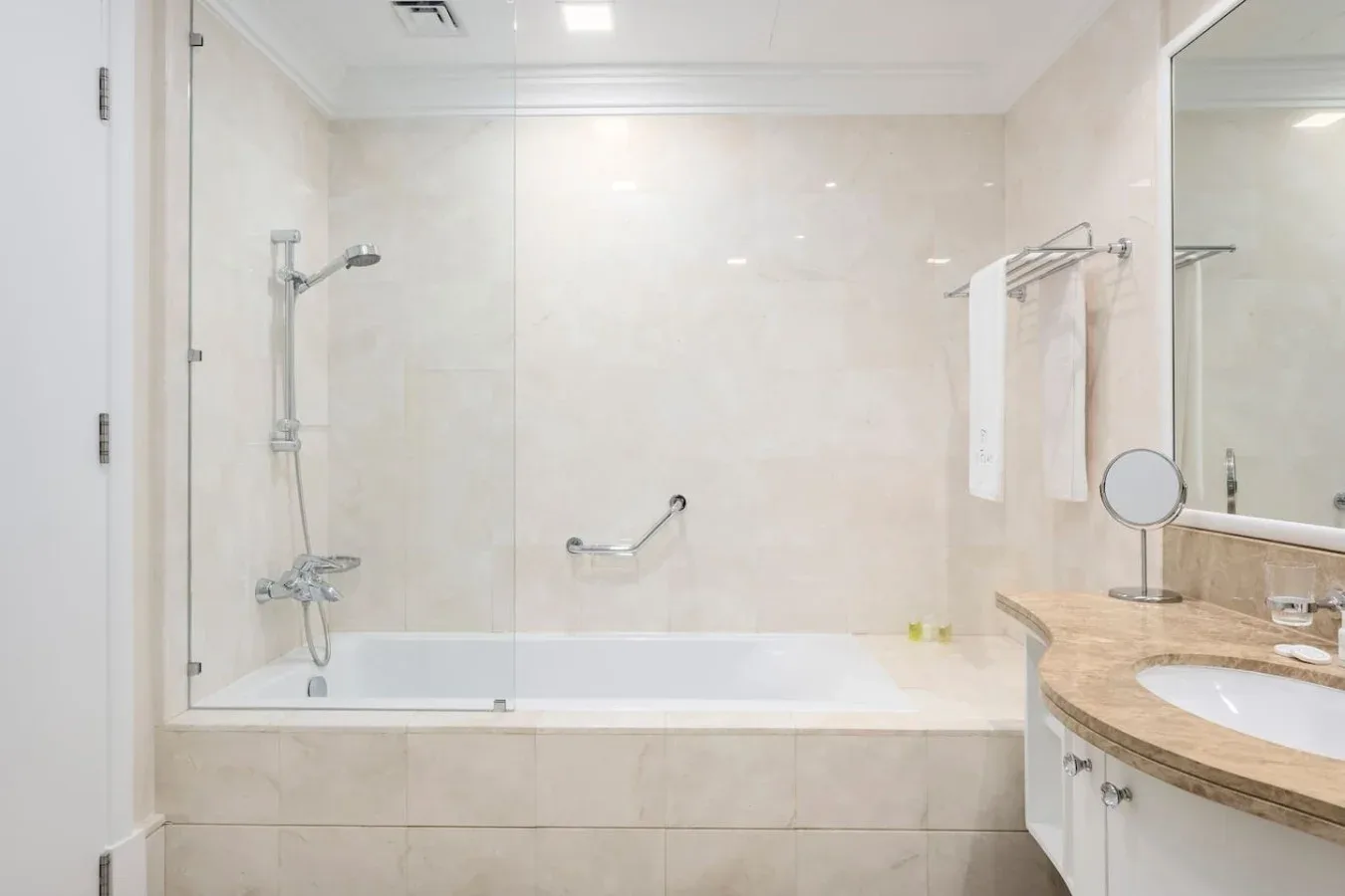 A bathroom with a bathtub, shower, and curved vanity.