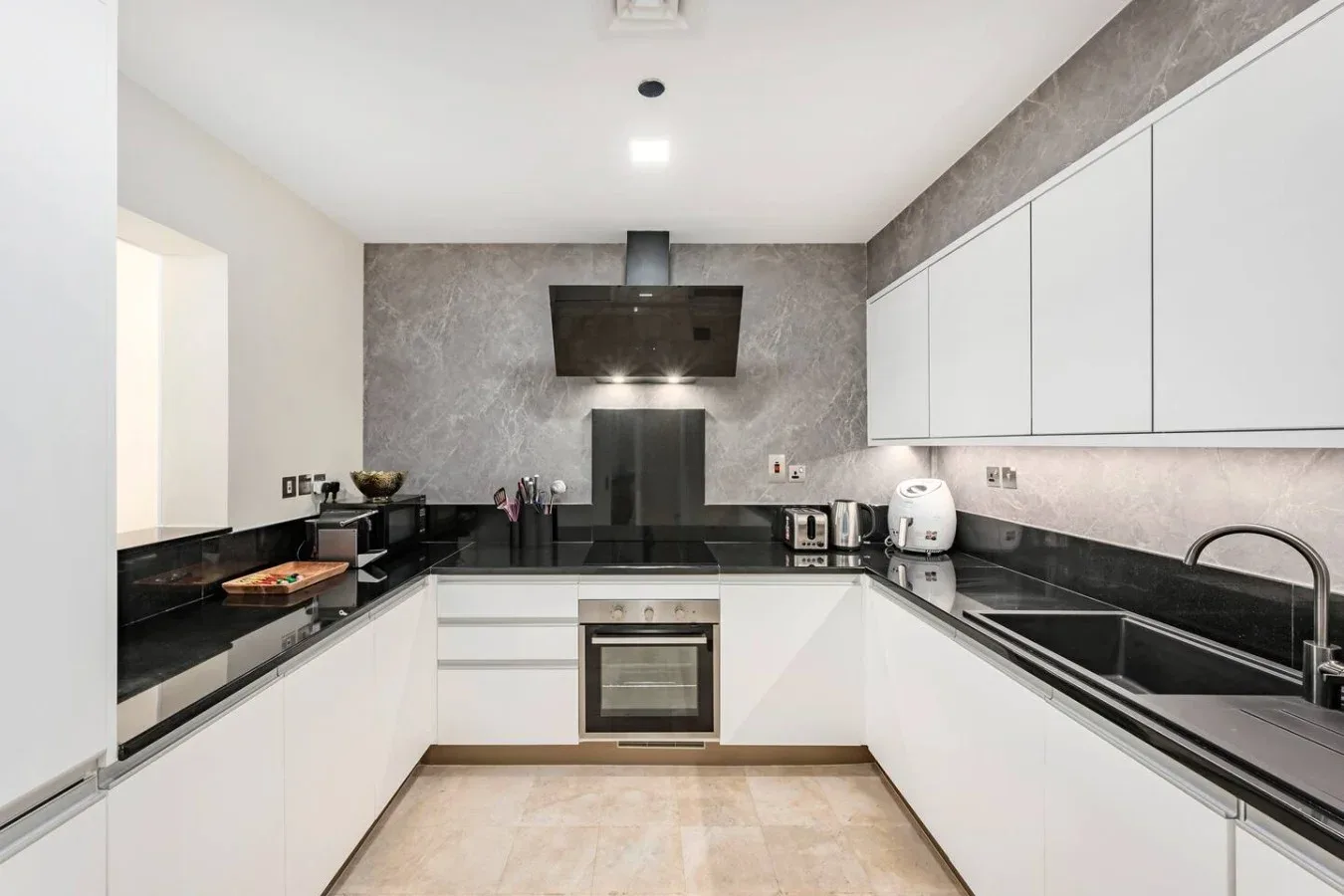 A modern kitchen with white cabinets and dark countertops.