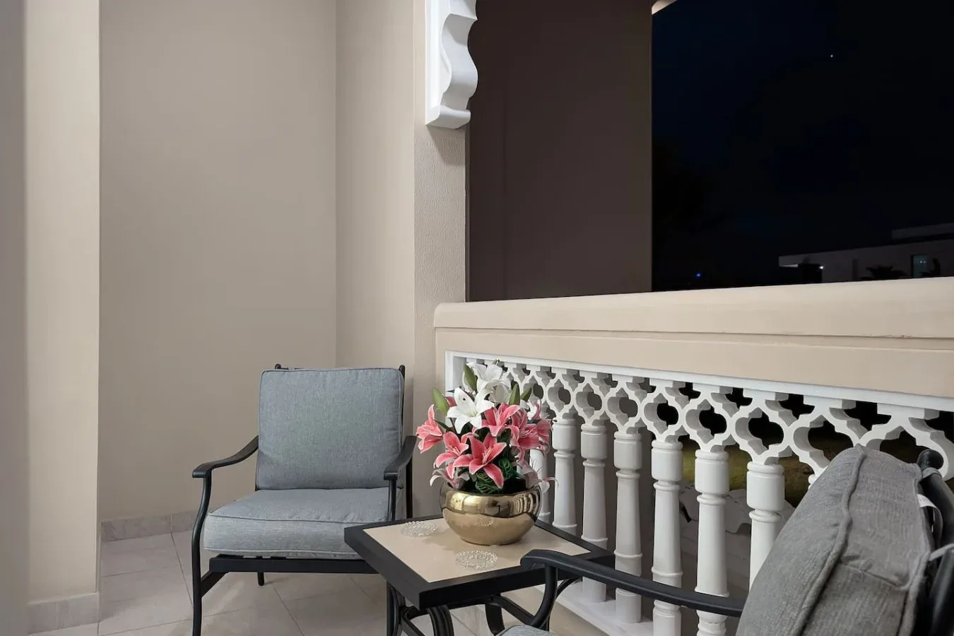 A seating area with a small table and flowers beside a decorative railing.