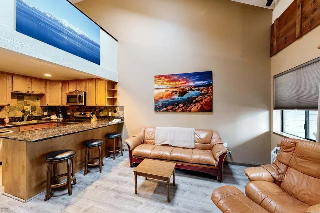 An open-plan living area with a tan sofa beside a kitchen counter.
