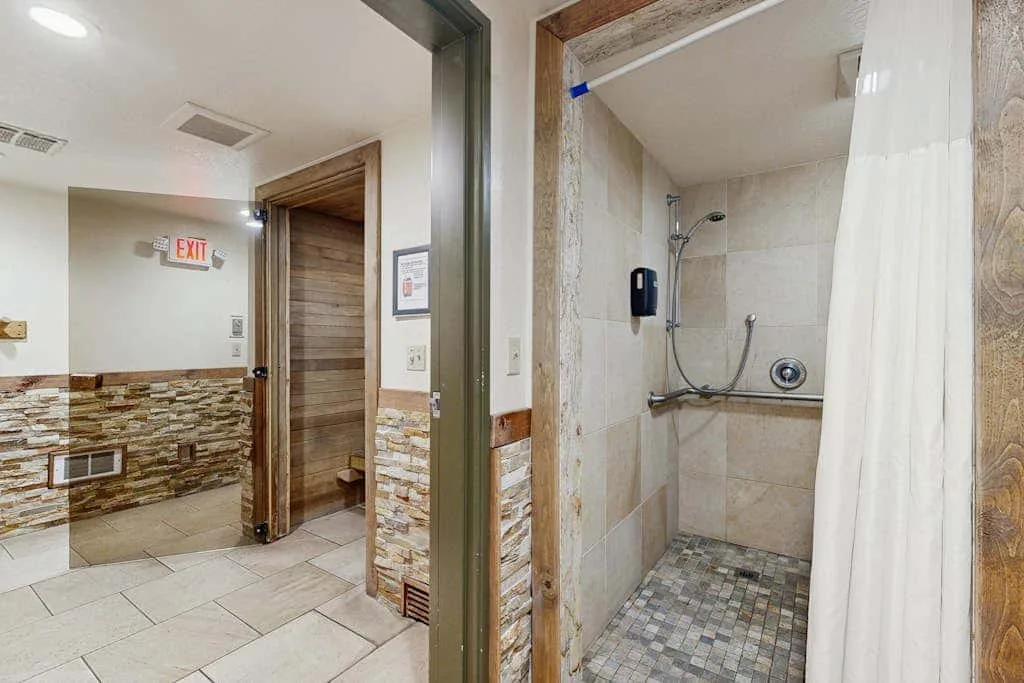 Un baño alicatado con una ducha y una cortina blanca.