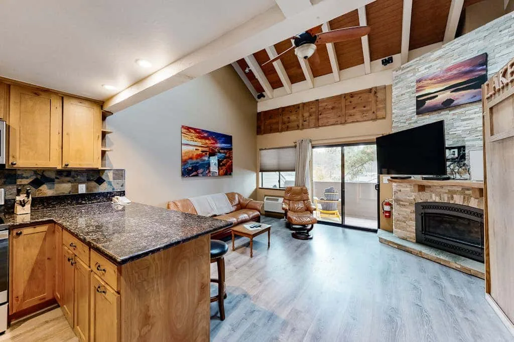 Una sala de estar y cocina de concepto abierto con techo abovedado y chimenea.