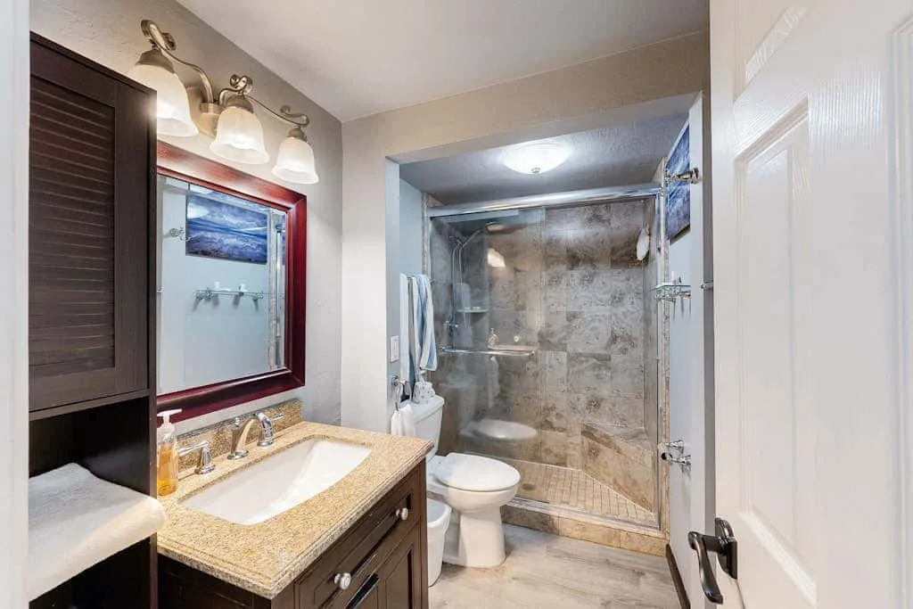 A bathroom with a vanity, toilet, and glass-enclosed shower.