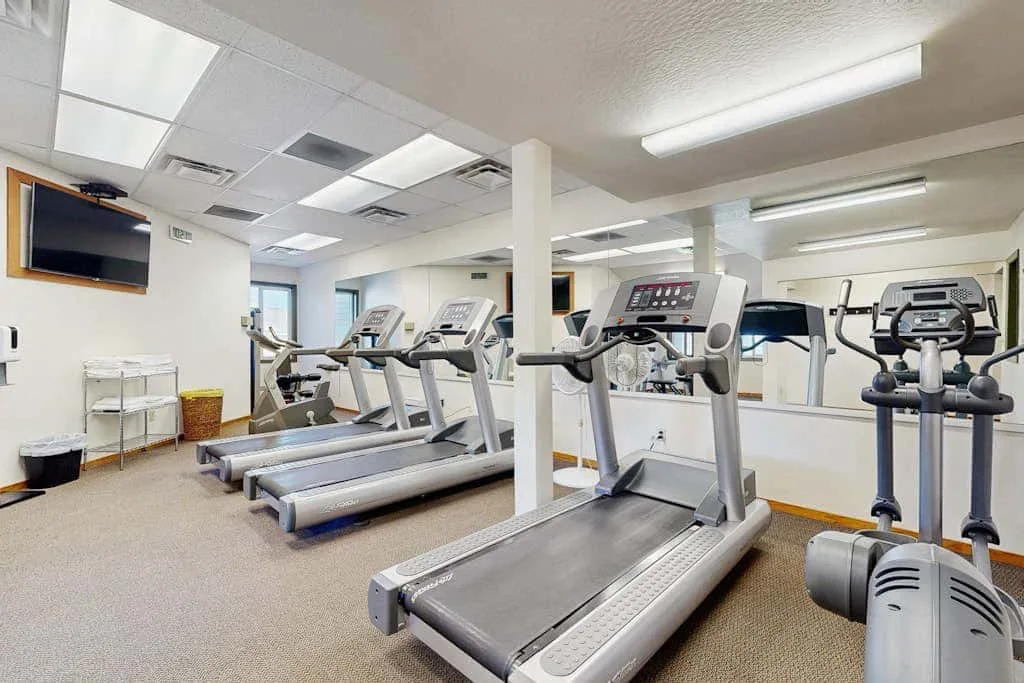 Una sala de ejercicio con caminadoras y otros equipos de entrenamiento.