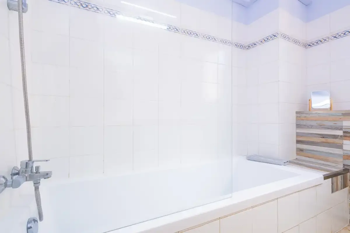 Un baño alicatado con bañera y ducha fijada a la pared.