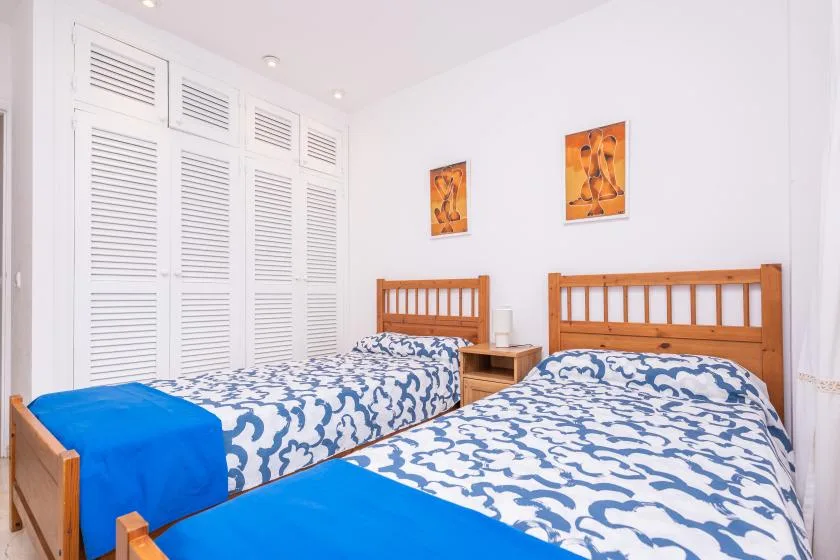 Un dormitorio con dos camas, ropa de cama estampada y armarios blancos con lamas.