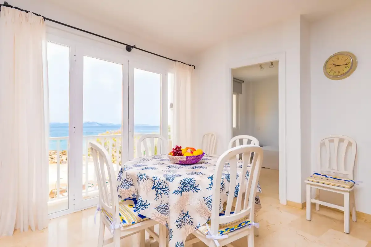 Un comedor con una mesa junto a puertas de cristal con vistas al mar.