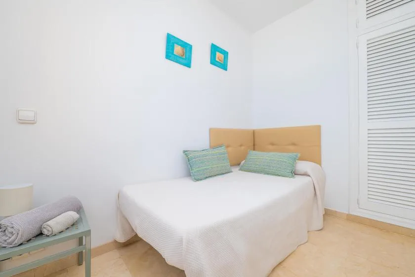 Un dormitorio con una cama bien tendida y dos pequeños adornos en la pared.