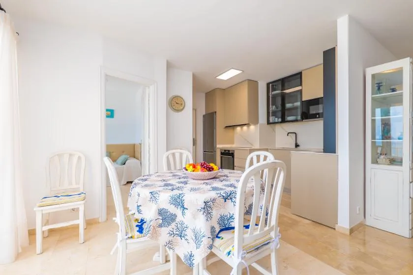 Un comedor con un mantel estampado y una cocina abierta al fondo.