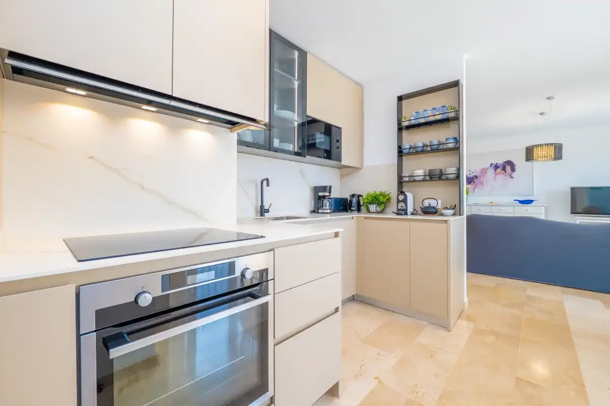 Una cocina moderna con armarios claros y una encimera se abre a un dormitorio.