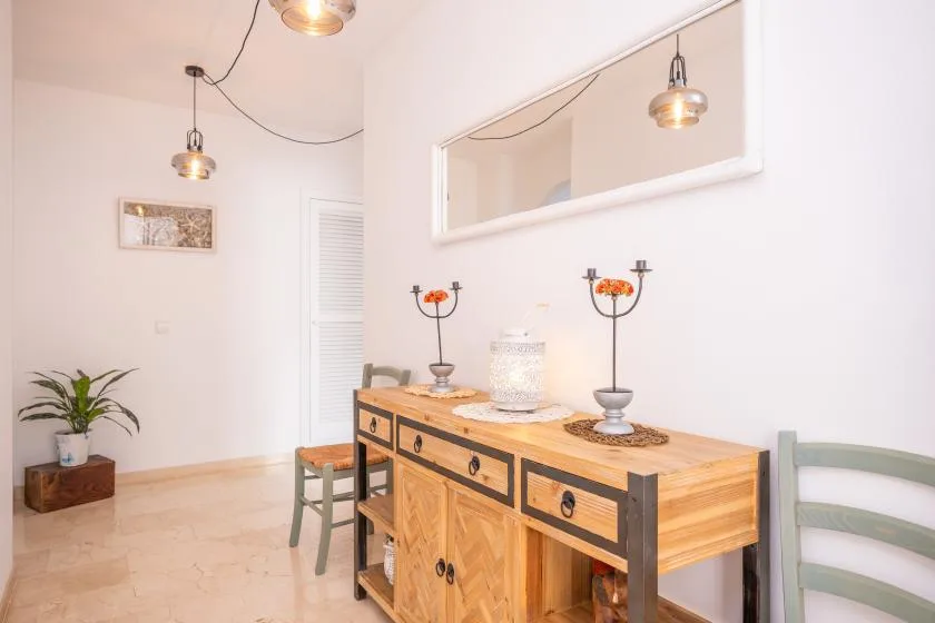 Un comedor luminoso cuenta con un aparador de madera bajo un gran espejo.