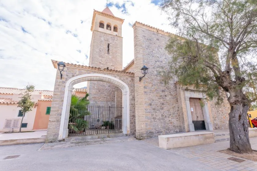 Entrada de una iglesia de piedra con un arco y un campanario.