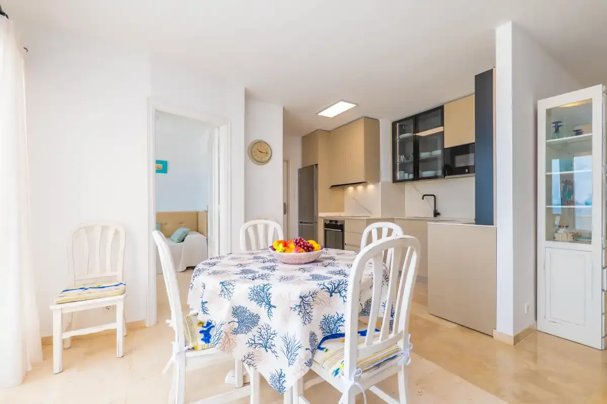 Un comedor con un mantel estampado está junto a una cocina abierta.