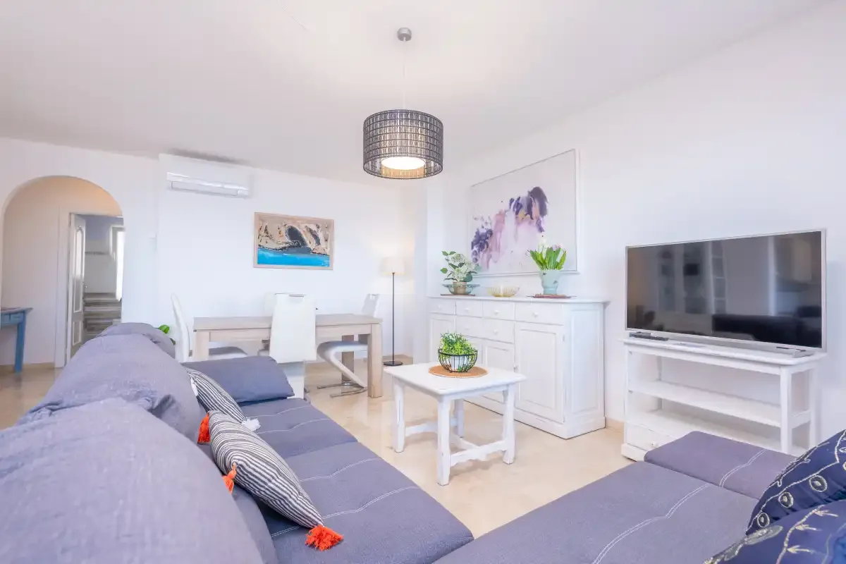 Una sala de estar luminosa con asientos, una mesa de centro y un televisor.
