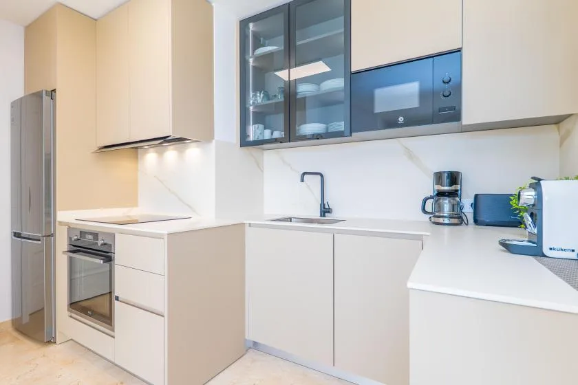 Una cocina moderna con gabinetes blancos, un refrigerador y una encimera.