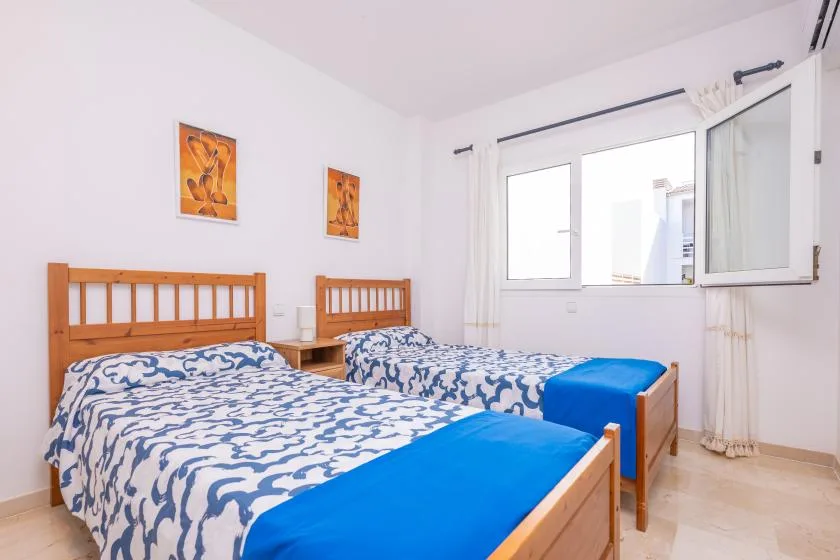 Un dormitorio con dos camas vestidas con ropa de cama estampada en azul y blanco.