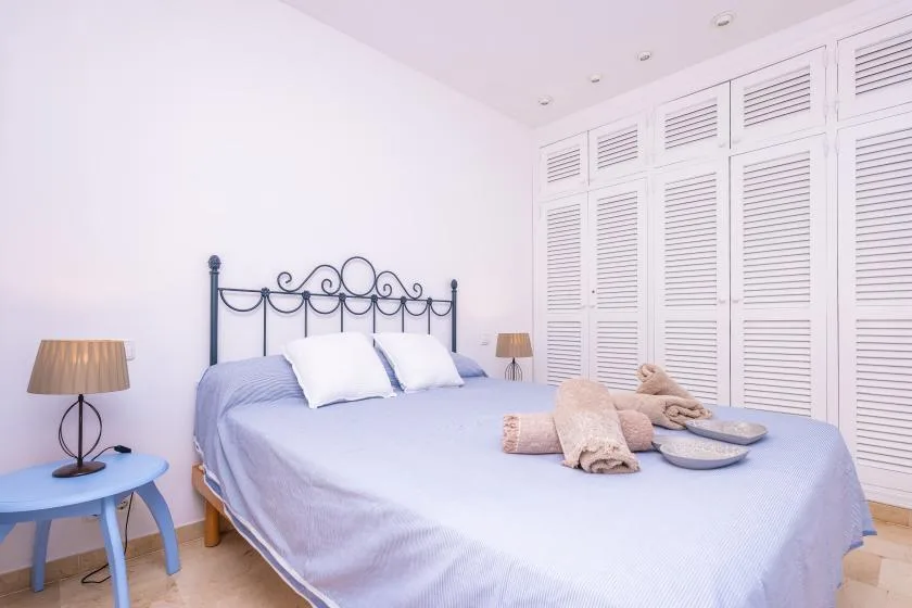 Un dormitorio luminoso con una cama bien hecha y puertas blancas de lamas.