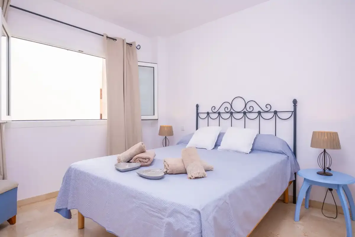 Un dormitorio con una cama doble, mesitas de noche y una ventana grande.
